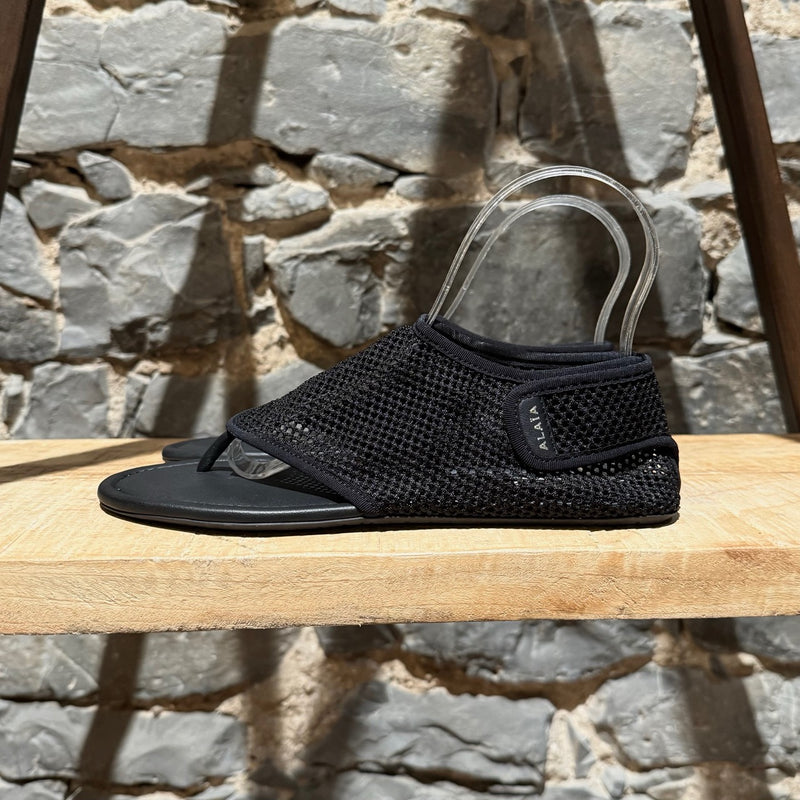 A side view of Alaïa Black Fishnet Mesh Thong Sandals