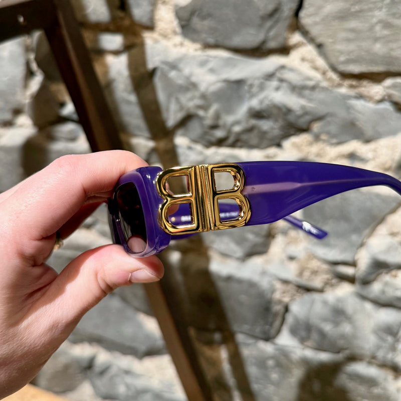 Side view of Balenciaga BB0096S Purple Dynasty Rectangular Sunglasses, showcasing the oversized gold-tone BB logo hardware on the glossy purple acetate temples.