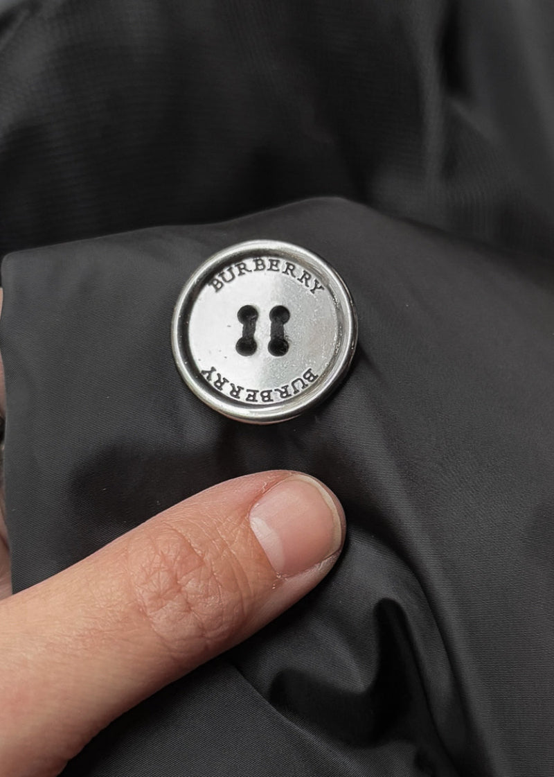 A branded button of Burberry Black Nylon Patent Piping Trench Coat