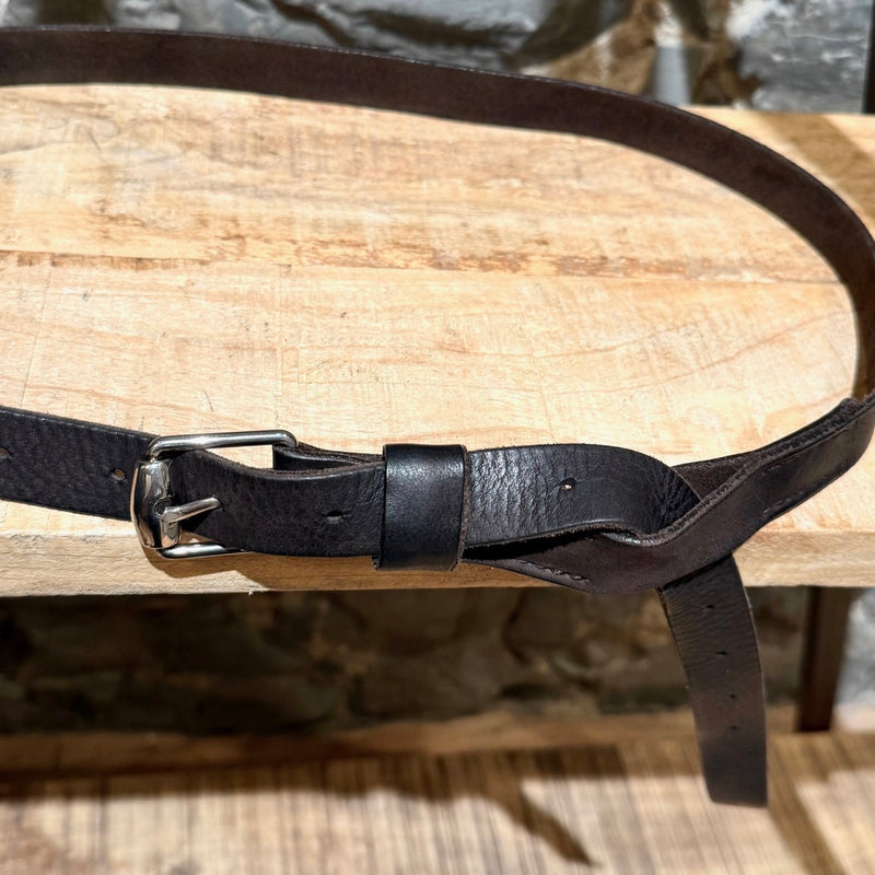 Gucci brown leather belt with silver-tone buckle, embossed branding, and adjustable strap, displayed on a wooden shelf.