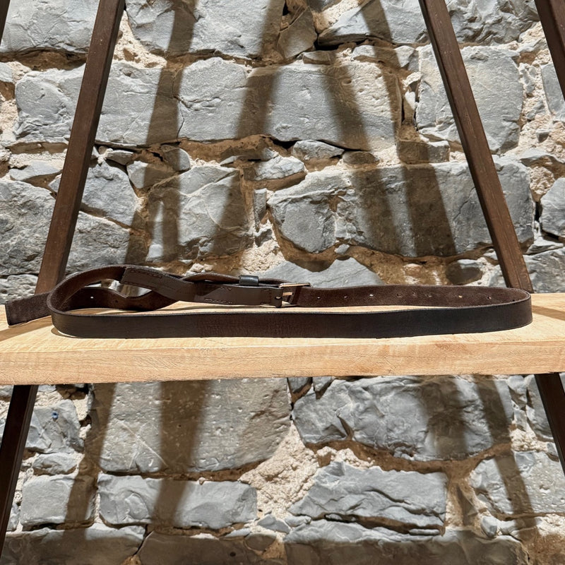 Gucci brown leather belt with silver-tone buckle, embossed branding, and adjustable strap, displayed on a wooden shelf.