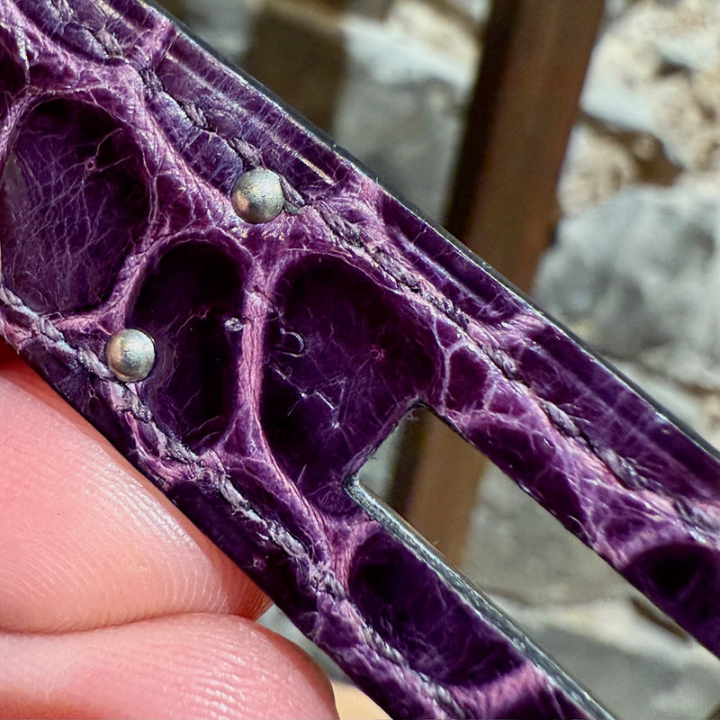 Detailed close-up of shiny porosus crocodile leather texture in amethyst hue on Hermès Birkin bag