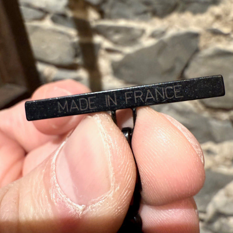 Close-up of the origin engraved on a black metal tag, attached to the chain of Lanvin Black Stone Satin Bow Chain Link Necklace