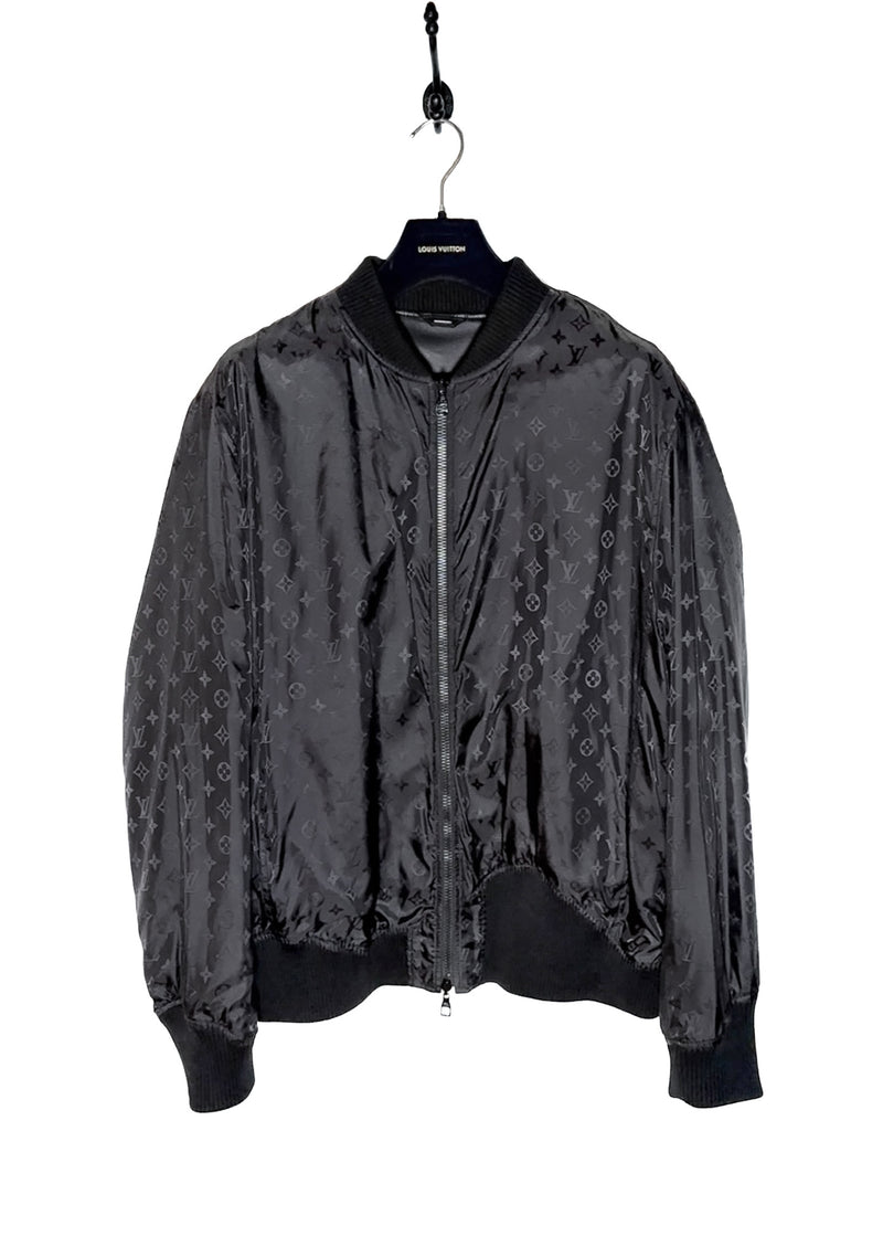 A Louis Vuitton black reversible jacket displayed on a hanger. One side features smooth black leather with ribbed cuffs, collar, and hem, while the other side reveals a black nylon fabric adorned with Louis Vuitton's signature monogram pattern. Close-up shots highlight the premium leather texture, monogram fabric, branded zipper pulls, and the Louis Vuitton logo label. Additional images show the jacket's reversible design, interior details, and stitching.