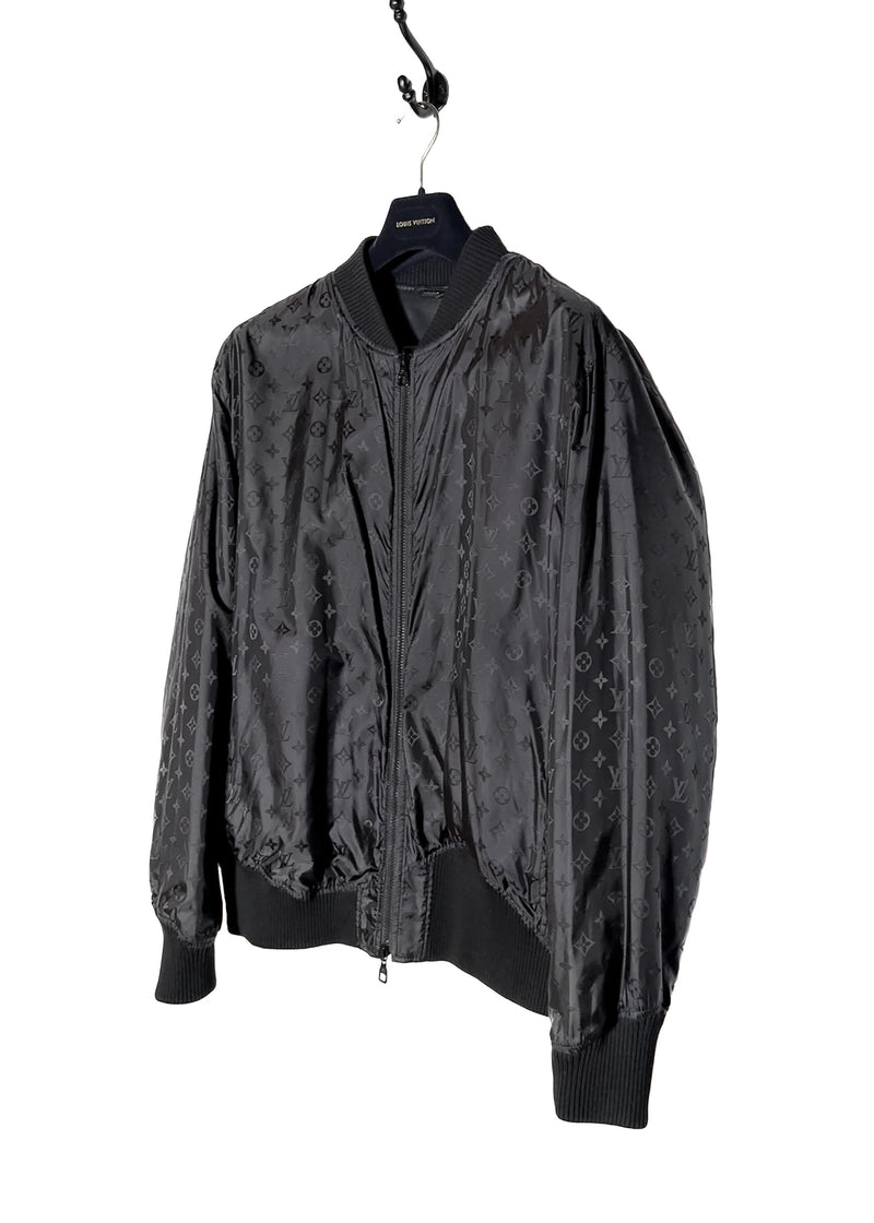 A Louis Vuitton black reversible jacket displayed on a hanger. One side features smooth black leather with ribbed cuffs, collar, and hem, while the other side reveals a black nylon fabric adorned with Louis Vuitton's signature monogram pattern. Close-up shots highlight the premium leather texture, monogram fabric, branded zipper pulls, and the Louis Vuitton logo label. Additional images show the jacket's reversible design, interior details, and stitching.