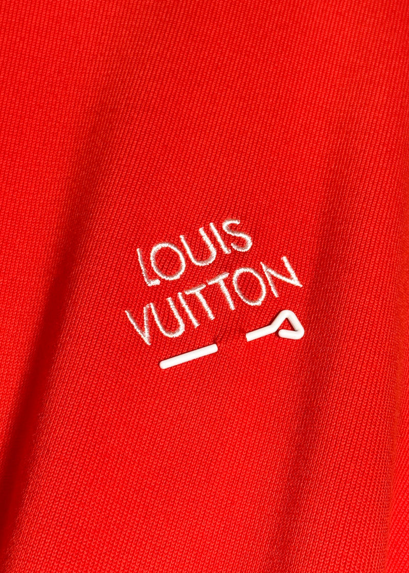 Close-up on branded logo and pin detail on chest of Louis Vuitton Orange Pin Logo Embroidered Knitted T-shirt