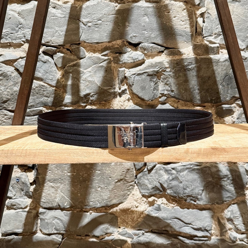 Prada black nylon belt with a silver-tone logo-engraved slide buckle, shown from various angles to highlight details such as the material, buckle engraving, and overall design.