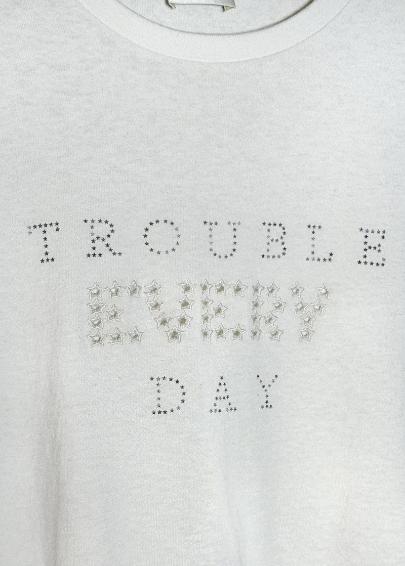 Embroidered TROUBLE EVERY DAY detail  close-up on chest of Saint Laurent SS20 Ivory "Trouble Every Day" Embroidered Cut-out Tank Top