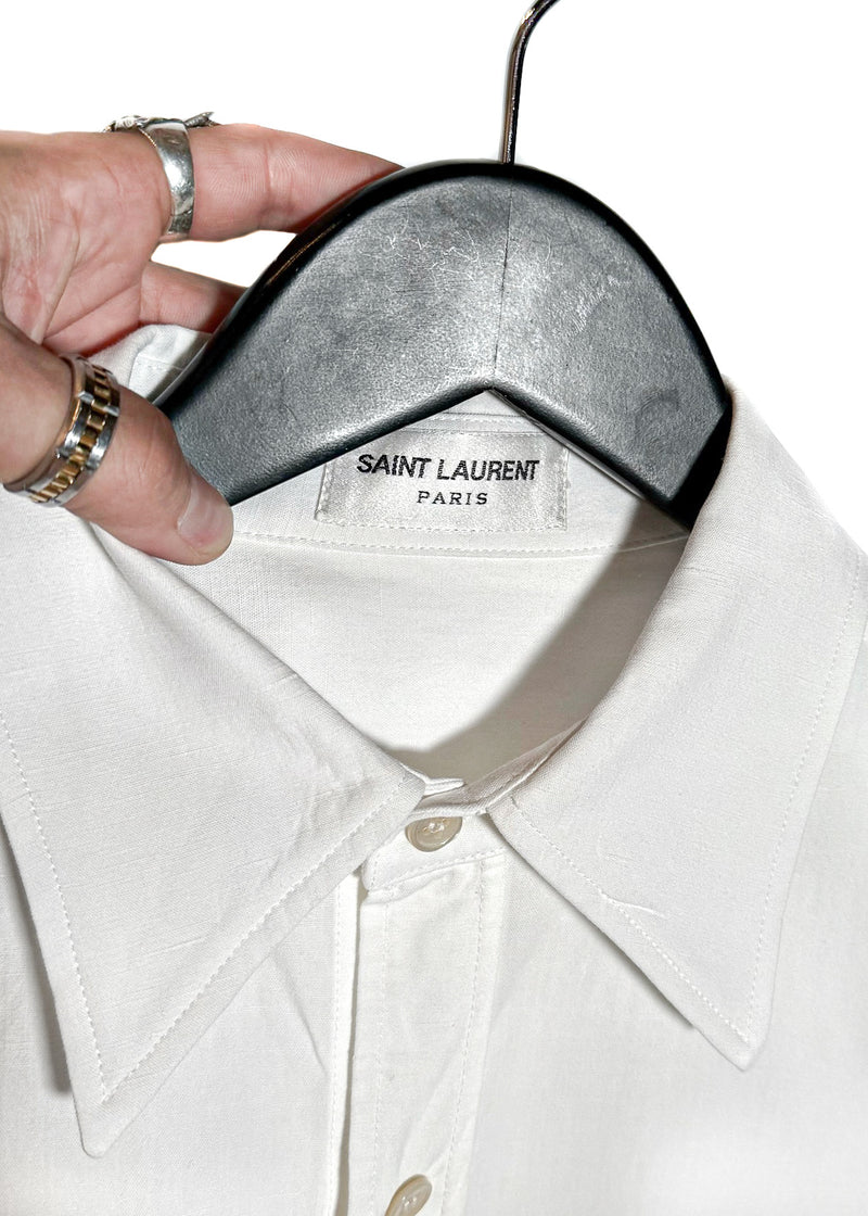 Saint Laurent YSL Logo White Linen Blend Buttoned Shirt. A white button-up shirt featuring a pointed collar, tonal embroidered YSL logo on the chest pocket, and engraved buttoned cuffs. Made in Italy, crafted from a linen-cotton blend, with a clean and lightweight silhouette.