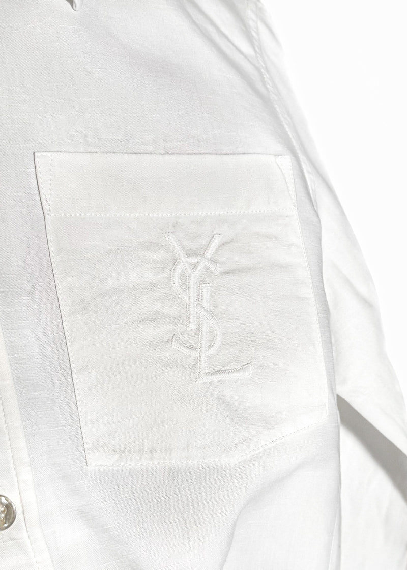 Saint Laurent YSL Logo White Linen Blend Buttoned Shirt. A white button-up shirt featuring a pointed collar, tonal embroidered YSL logo on the chest pocket, and engraved buttoned cuffs. Made in Italy, crafted from a linen-cotton blend, with a clean and lightweight silhouette.