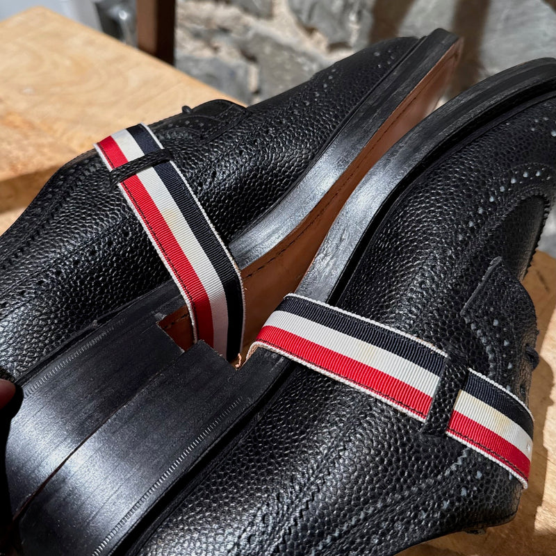 Close-up on Thom Browne Black Pebbled Grosgrain Tricolour Strap Long Wingtip Shoes