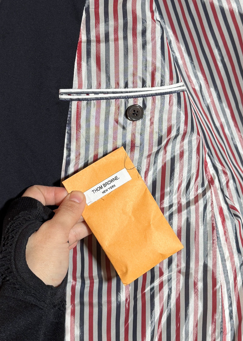 A sealed orange envelope with a Thom Browne New York label containing spare buttons or fabric swatches of Thom Browne Navy Blue 4 Bands Wool Suit