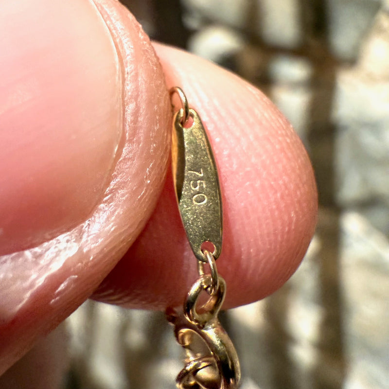 A close-up of the necklace’s clasp with the "750" hallmark engraved on the gold tag.