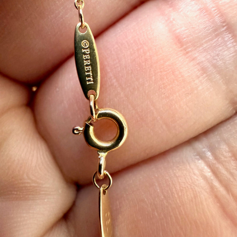 A close-up of the gold tag engraved with "Peretti," attached to the necklace’s clasp.