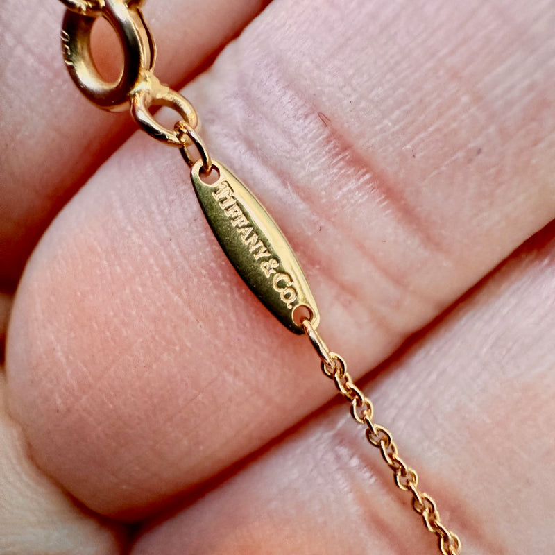 A close-up of the gold tag engraved with "Tiffany & Co.," attached to the necklace’s clasp.