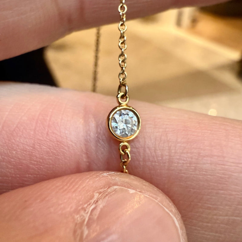 A close-up of a diamond station on the Tiffany & Co. necklace, showing the bezel-set round diamond in 18k yellow gold.