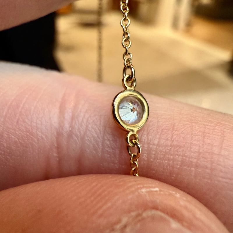 A close-up of a diamond station on the Tiffany & Co. necklace, showing the bezel-set round diamond in 18k yellow gold.