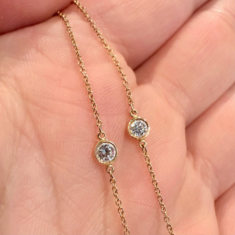 A close-up of a diamond station on the Tiffany & Co. necklace, showing the bezel-set round diamond in 18k yellow gold.