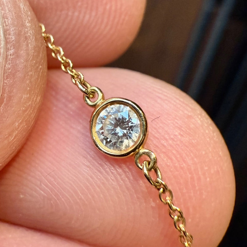 A close-up of a diamond station on the Tiffany & Co. necklace, showing the bezel-set round diamond in 18k yellow gold.